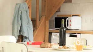 A dining area with a wooden staircase, a microwave, and a table with chairs.
