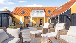 A courtyard with wicker furniture, a wooden deck, and a building with orange tiled roofs. - "Albine" - 150m from the sea by Interhome (Skagen)