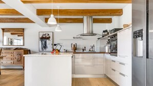 A modern kitchen with white cabinetry, a central island, stainless steel appliances, and wooden beams on the ceiling. - "Albine" - 150m from the sea by Interhome (Skagen)