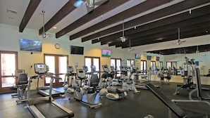 Une salle de sport équipée de tapis de course, de vélos elliptiques et d’appareils de musculation.