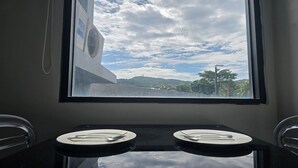 Une salle de bain avec deux lavabos, une fenêtre donnant sur un pont et sur la verdure, et un appareil de climatisation.