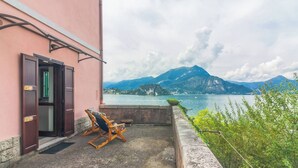 A balcony with a wooden chair and a door, overlooking a lake and mountains. - Varenna Wonders  (Varenna)