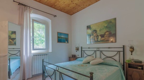 Un dormitorio con cama, ventana, radiador y obras de arte en las paredes.