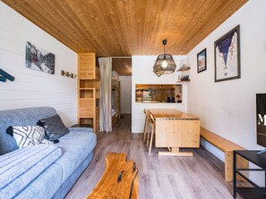 A cozy interior with a wooden ceiling, a sofa, a dining table, and a kitchen area. - Central studio 3-4 ppl, near slopes, balcony (Val-d'Isère)