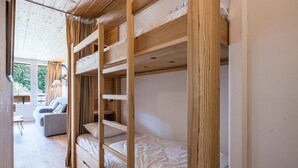 A bunk bed room with a wooden ceiling and a window.