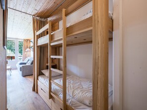 A bunk bed room with a wooden ceiling and a window.