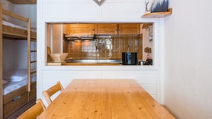 A compact kitchen with a wooden table, built-in cabinets, and a window overlooking the interior.