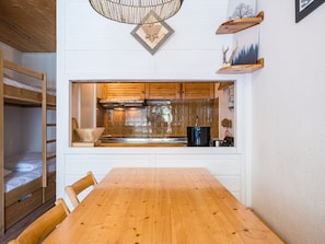 A compact kitchen with a wooden table, built-in cabinets, and a window overlooking the interior.