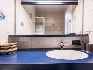 A bathroom with a blue countertop, a white sink, a mirror, and decorative tiles. - Central studio 3-4 ppl, near slopes, balcony (Val-d'Isère)