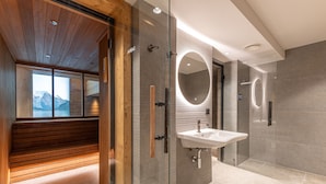 Ein modernes Badezimmer mit einer Holzbank, einer Glasdusche und einem großen Spiegel.