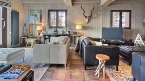 A spacious living room with a fireplace, a television, and a dining area with a table and chairs. - Spacious chalet with terrace and jacuzzi, near slopes for 14 people (La Plagne 1800)