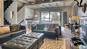 A spacious living area with a high ceiling, a staircase, and a large window providing a view of the outdoors. - Spacious chalet with terrace and jacuzzi, near slopes for 14 people (La Plagne 1800)