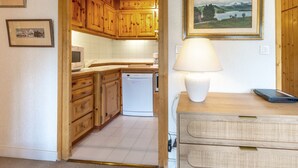 A kitchen with wooden cabinets, a dishwasher, a microwave, and a table with a lamp.