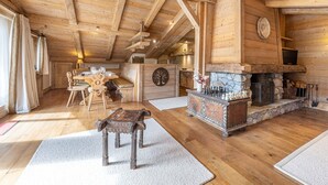 Un intérieur en bois avec une cheminée, une table à manger et un banc.