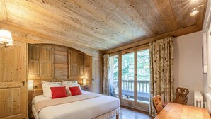 Une chambre à coucher en bois, avec un grand lit, une table en bois et une fenêtre avec des rideaux.