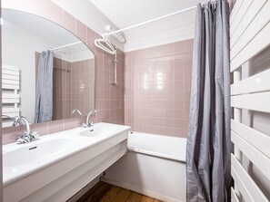 Une salle de bain avec un lavabo blanc, un miroir et une douche.