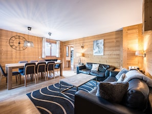 A cozy cabin interior with a dining area, a sofa, and a fireplace.