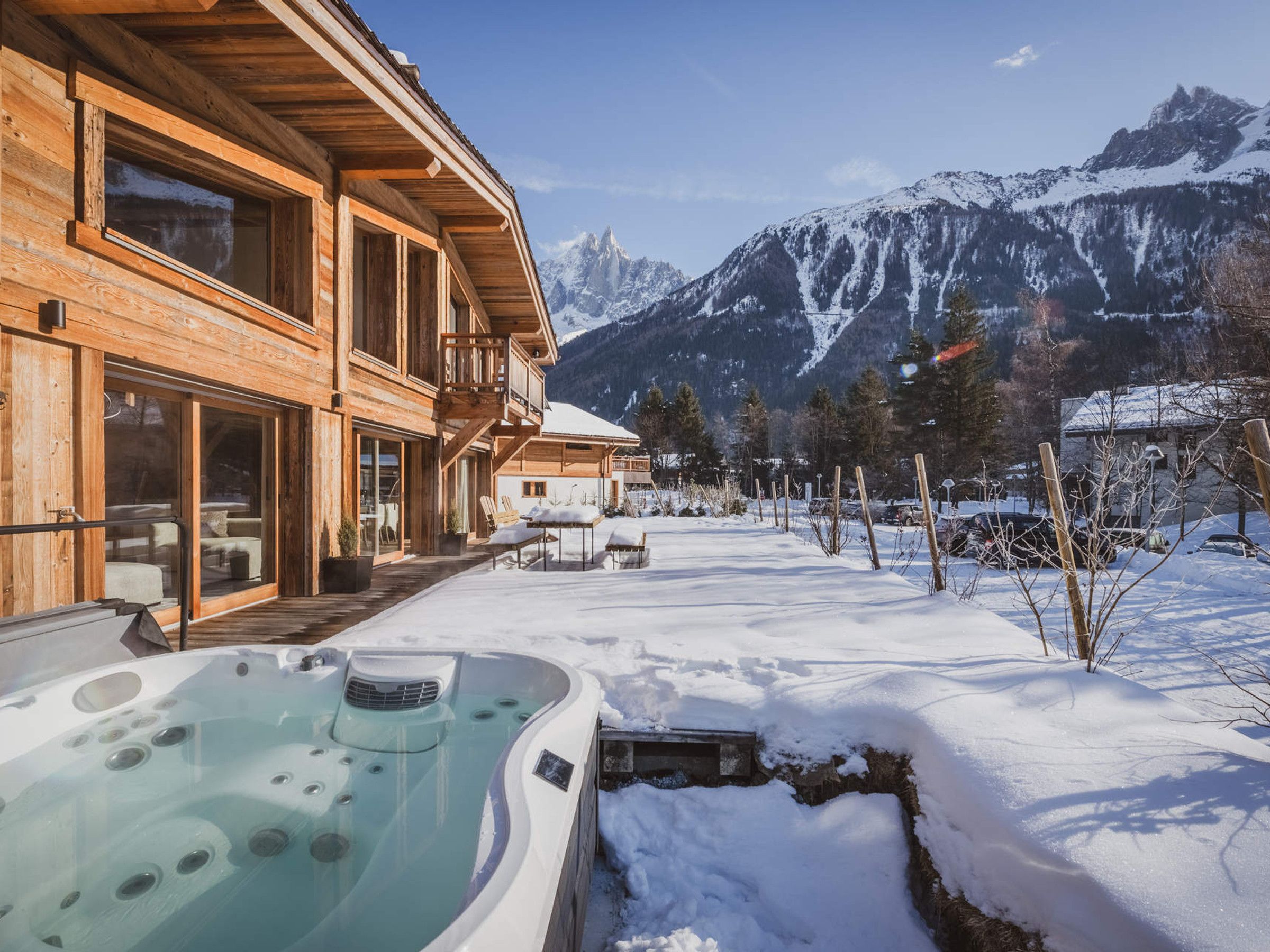 A wooden building with a hot tub and a view of snow-covered mountains.