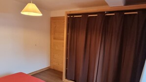 A room with two beds, a wooden door, and a curtain. - Cozy apartment in Les Gets, 4 pers, with parking (Les Gets)
