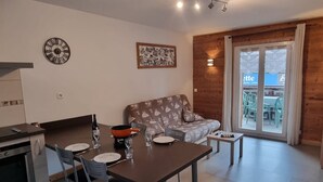 A modern kitchen with a dining table set for two, a sofa, and a small coffee table. - Cozy apartment in Les Gets, 4 pers, with parking (Les Gets)
