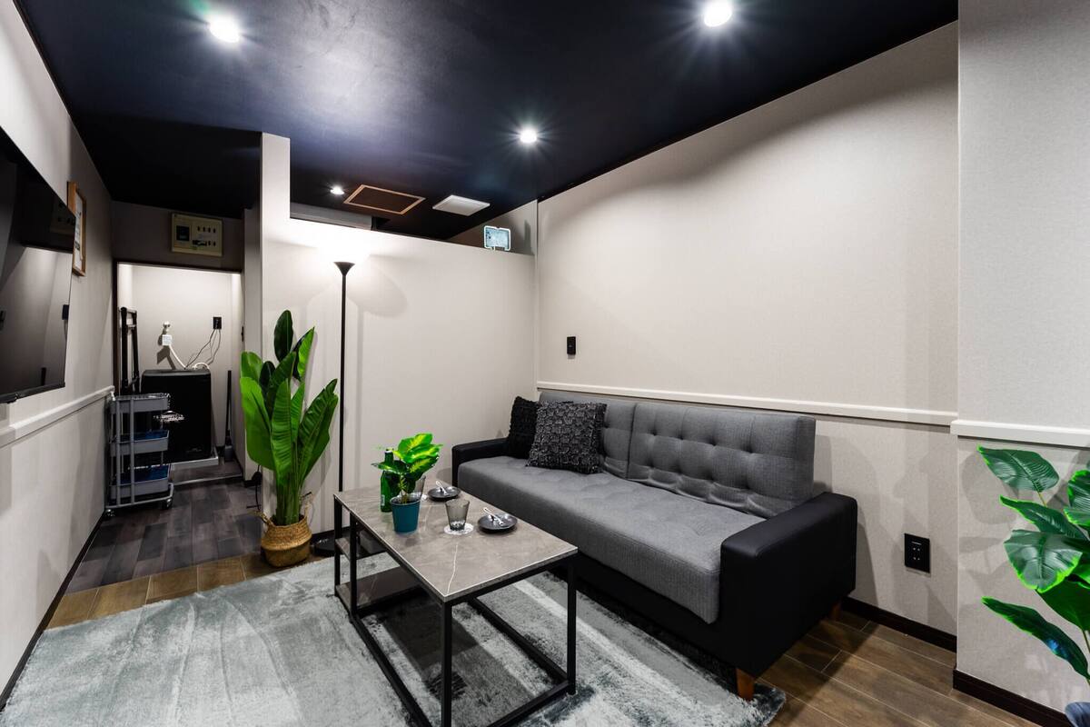 A modern living room with a grey sofa, a coffee table, and a large green plant.