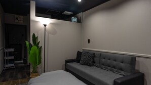 Un dormitorio moderno con cama, sofá, lámpara de pie y planta en maceta.