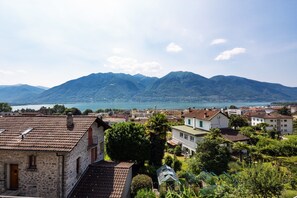 A town with stone buildings, a lake, and mountains in the background. - Honeymoon Love Retreat 2 (Minusio)