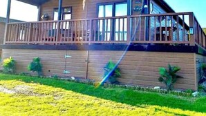 A two-story wooden cabin with a balcony, large windows, and a covered porch. - Lodge - Sleeps up to 6, pet Friendly & bbq Allowed (Pwllheli)