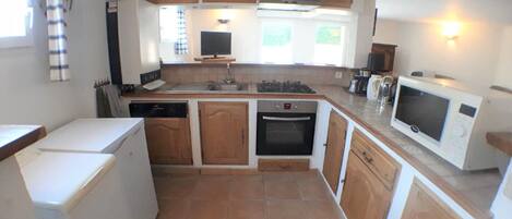 A compact kitchen with wooden cabinets, a dishwasher, an oven, a microwave, and a sink.