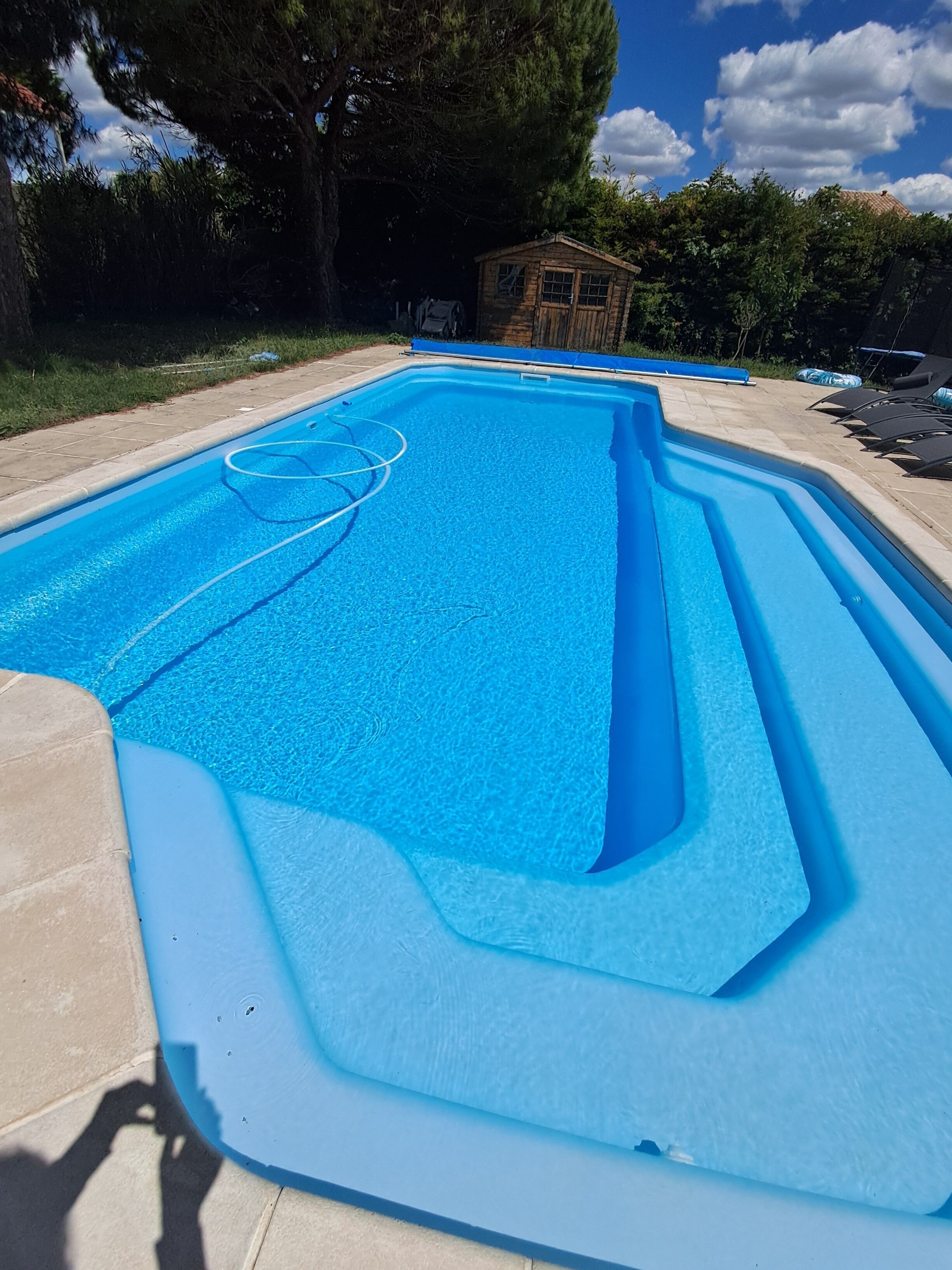 Une piscine rectangulaire à l’eau d’un bleu limpide, entourée d’une terrasse carrelée.