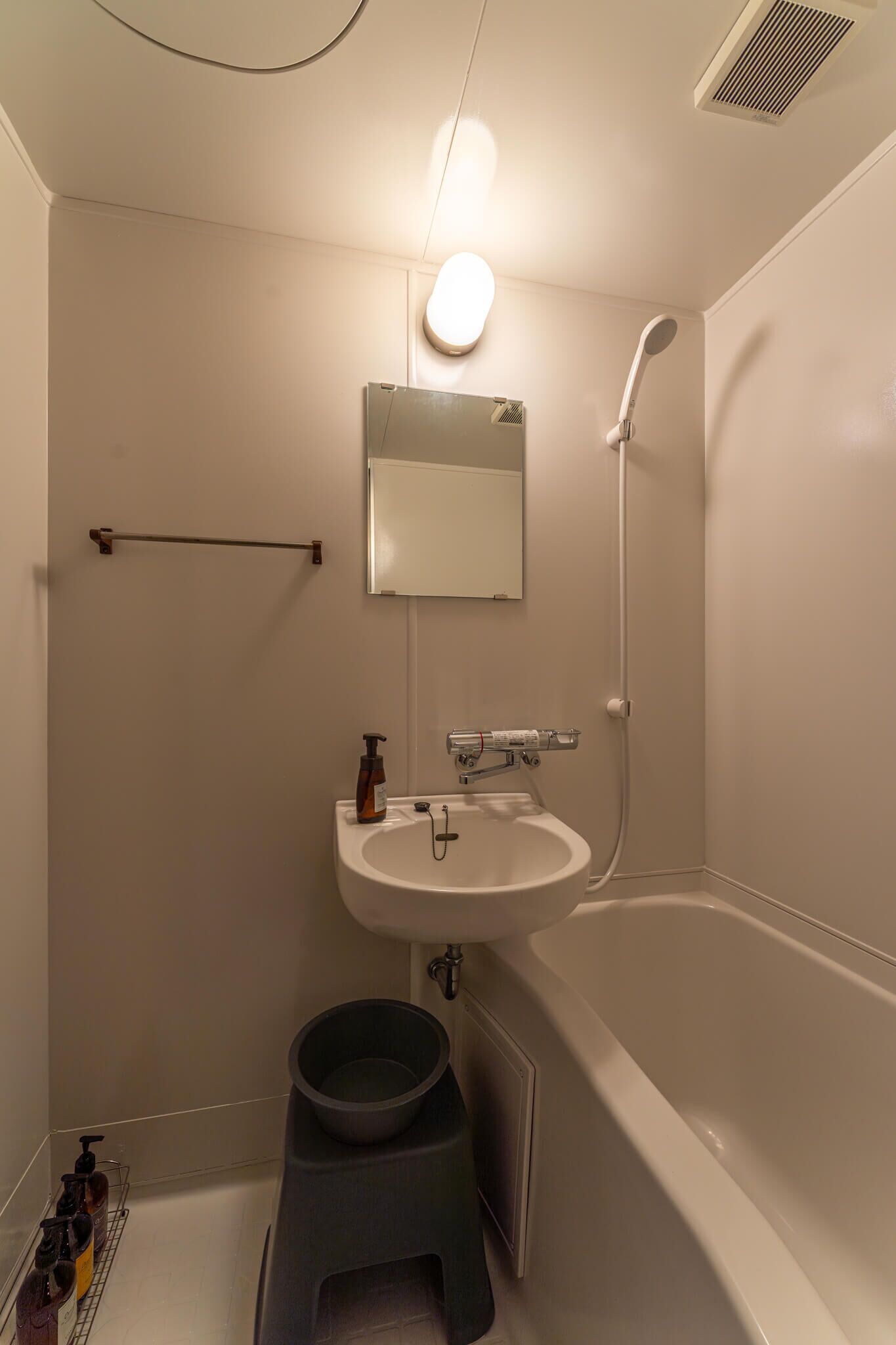 Un baño con lavamanos, espejo y ducha blancos.