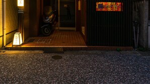 A modern building with a dark facade, a motorcycle parked outside, and a brightly lit signboard. - Oyado Kinokuniya Shindaikumachi (Nagasaki)