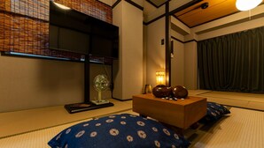 A traditional Japanese room with tatami flooring, a low wooden table, and a fan. - Oyado Kinokuniya Shindaikumachi (Nagasaki)