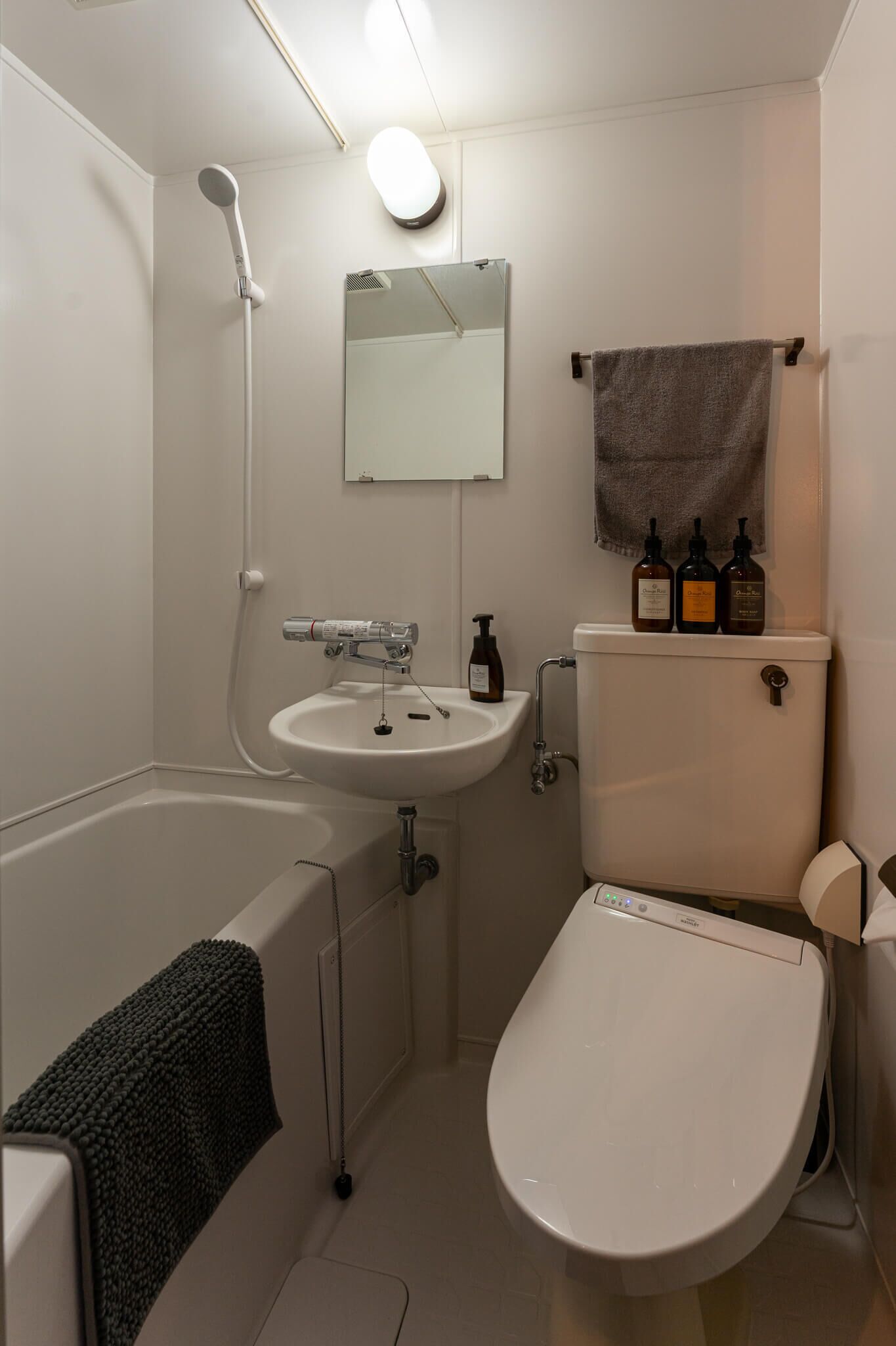 A compact bathroom with a bathtub, a sink, a toilet, and a mirror.
