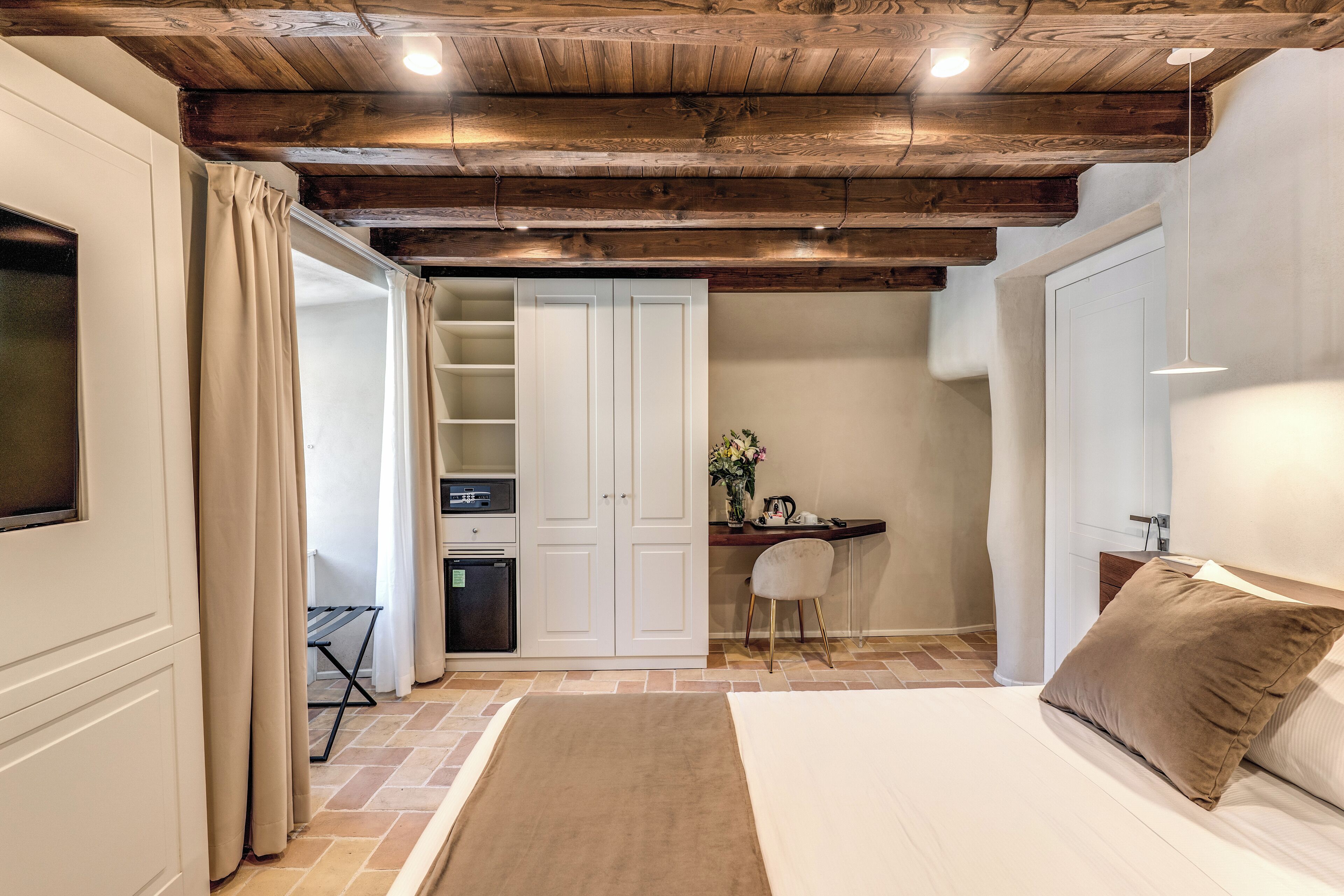 A bedroom with a bed, a desk, and a wardrobe.