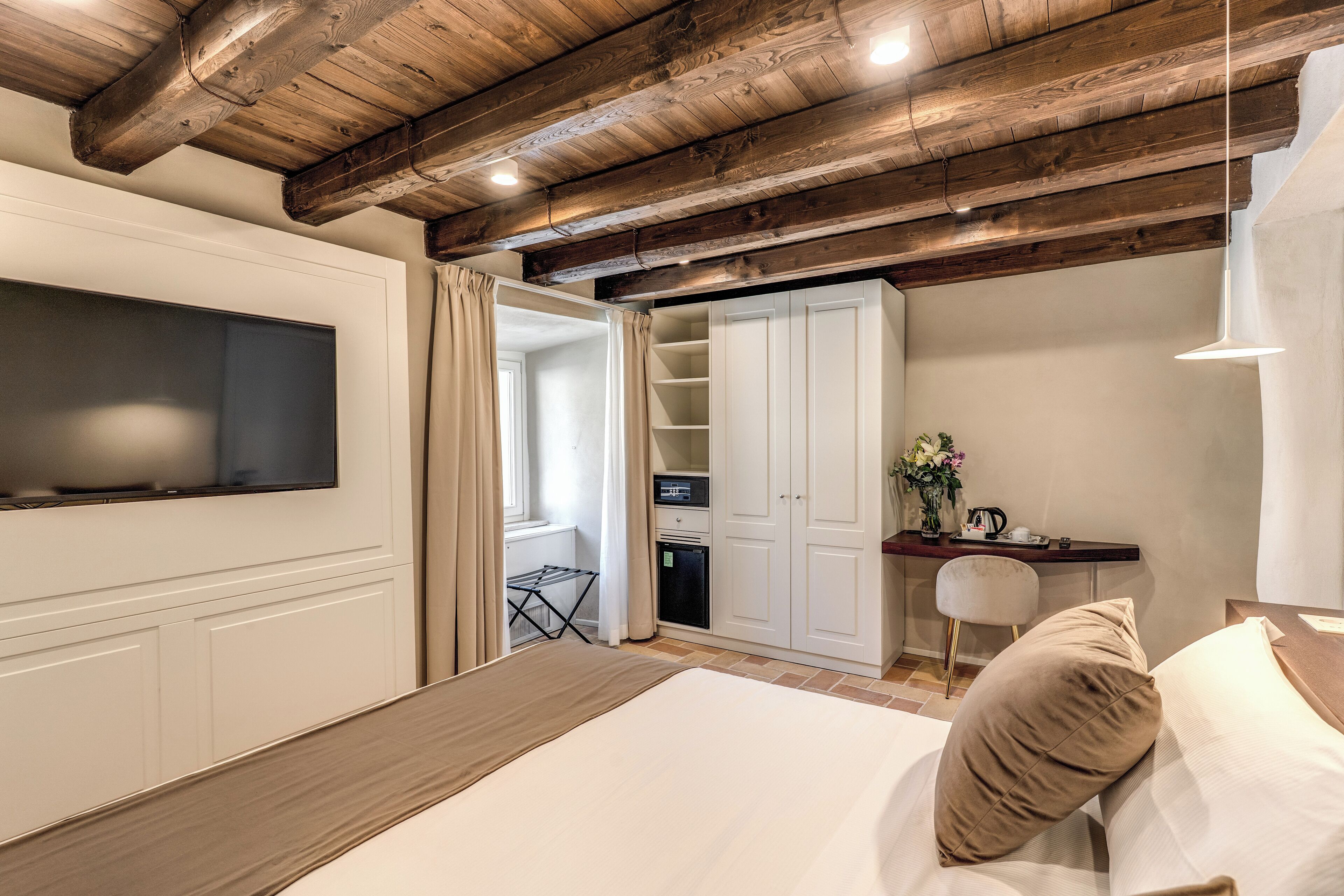 Une chambre à coucher comprenant un lit, un téléviseur fixé au mur, un bureau avec une chaise et une armoire.