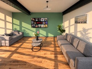 A living room with a sectional sofa, a coffee table, and a wall-mounted TV displaying Netflix content.