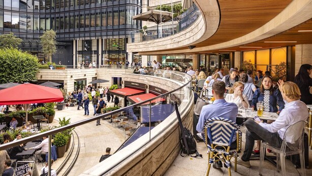 Een modern gebouw met een gebogen glazen gevel, terrassen en een zichtbaar restaurant genaamd 'YAUATCHA'.