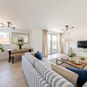 Una sala de estar moderna con un sofá, una mesa de comedor y un televisor.