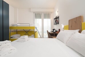 A hotel room with a bunk bed, a desk with a chair, a coffee machine, and a window with curtains. - Bel Fiore 58 (Florence)
