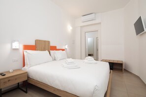 A hotel room with a bed, bedside tables, an air conditioning unit, a TV, and a mirror. - Bel Fiore 58 (Florence)
