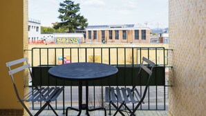 A balcony with a table and chairs, a view of a building with graffiti, and a tree in the background. - Bel Fiore 58 (Florence)