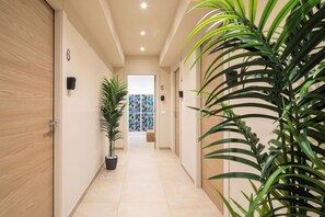 A hallway with a potted plant, a door with a number, and a colorful wall. - Bel Fiore 58 (Florence)