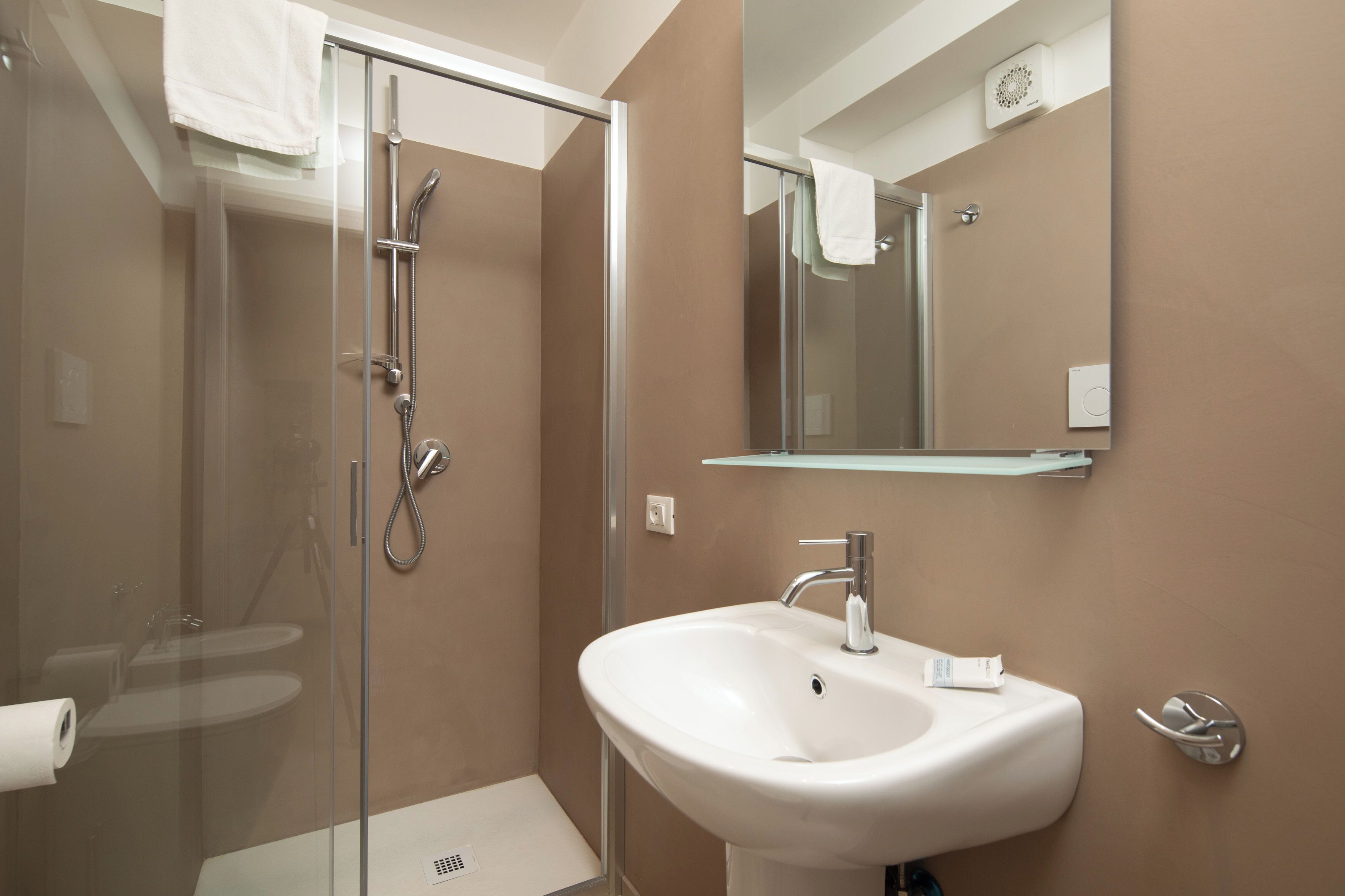 A modern bathroom with a glass-enclosed shower, a white sink, and a mirror above the sink.
