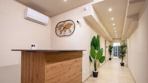 A reception desk with a wooden finish, a world map artwork on the wall, and potted plants along a hallway. - Bel Fiore 58 (Florence)