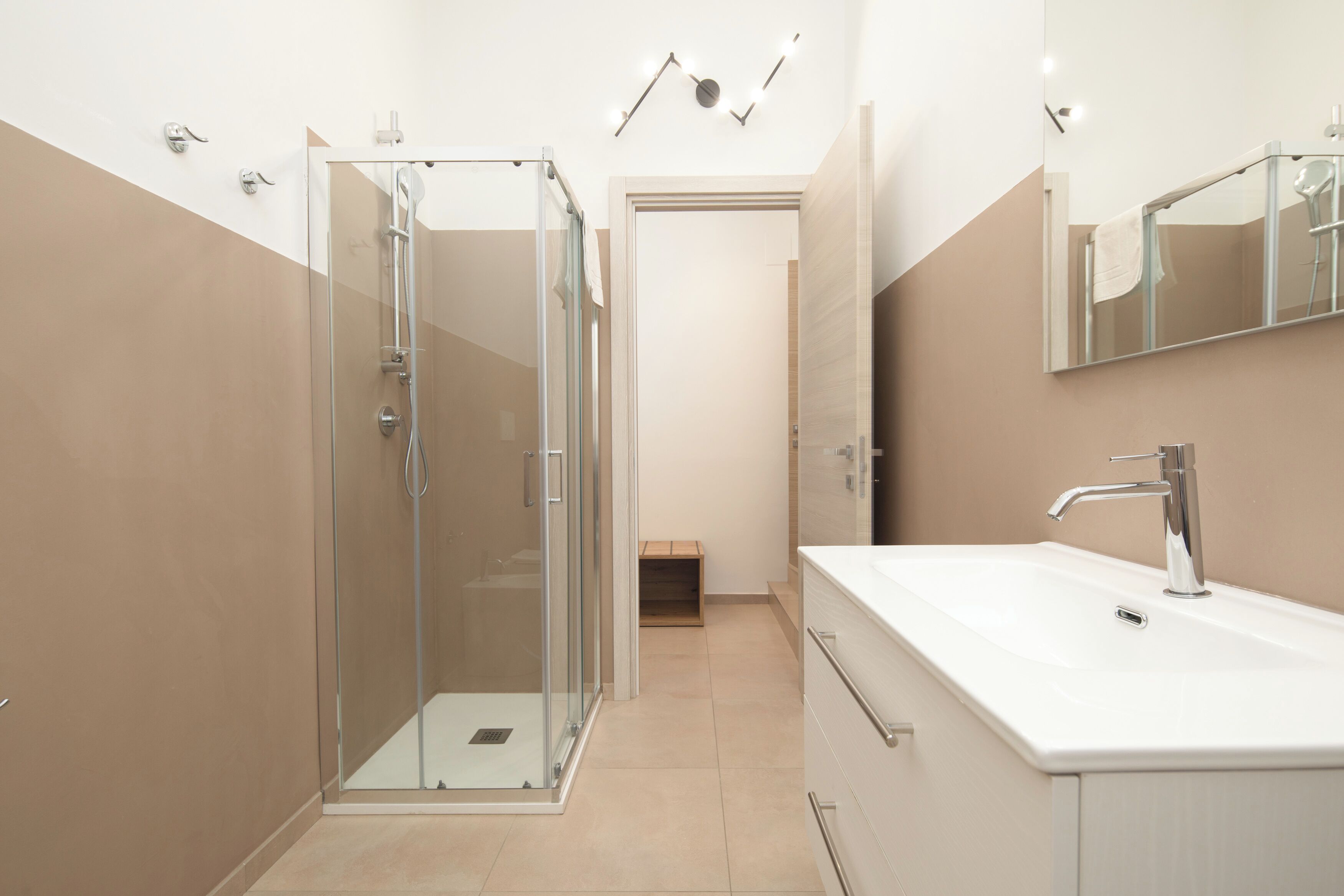 A modern bathroom with a glass-enclosed shower, a white sink, and a mirror above it.