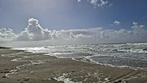 En strand med vågor, en klar himmel och en sol.