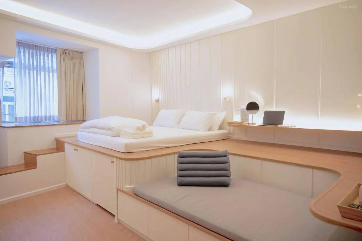 A modern bedroom with a bed, a seating area, and a desk with a lamp.