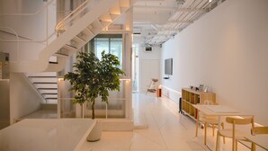 A modern interior with a staircase, a plant, a TV, and a wooden table with chairs. - Vaeh Viean Silom (Bangkok)