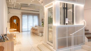A modern interior with a staircase, a wooden door, and a dining area with stools. - Vaeh Viean Silom (Bangkok)